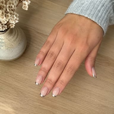 A hand with a freshly finished chrome French manicure.