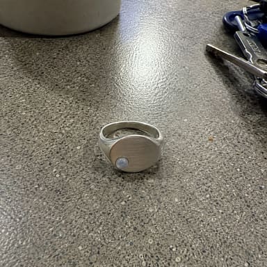 A silver signet ring photographed on a kitchen worktop.